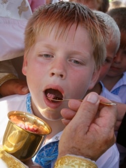 A boy receives communion from a Ukrainian Greek Catholic priest in the village of Krylos, western Ukraine, in July 2012.