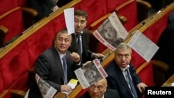 Ukrainian deputies look on as a supporter of jailed Yulia Tymoshenko scatters leaflets with a portrait of her during a session of the parliament in Kyiv on November 19.