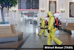 Russian government workers disinfect a Moscow train station as authorities step up efforts to curb a new surge in coronavirus cases.