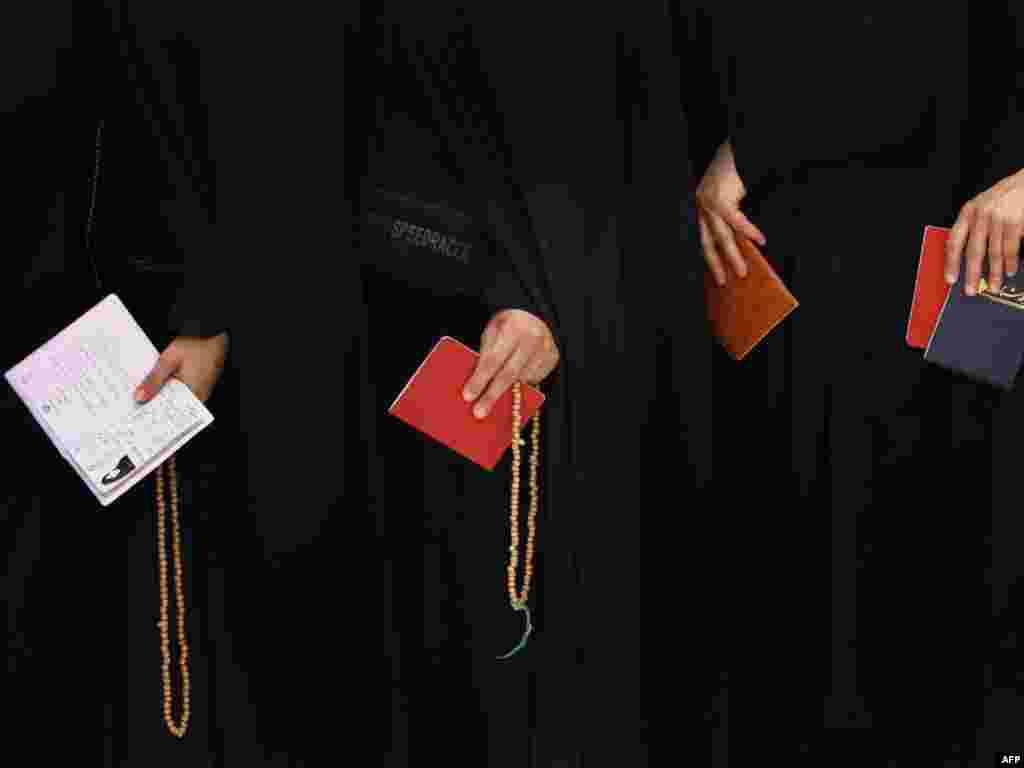 Iranian women hold prayer beads and registration cards as they wait to vote in Qom.