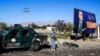 An Afghan security official stands beside a billboard featuring vice-presidential candidate Amrullah Saleh as he inspects the scene of a suicide bombing that targeted a campaign rally of the incumbent president.