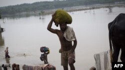 Pakistani farmers carry belongings from their destroyed houses to tents set on a highway on the outskirts of Peshawar.