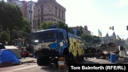 A water cannon truck that was captured and destroyed by activists still stands on the square.