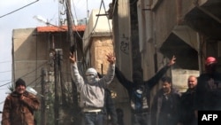 Antigovernment activists gesticulate as they gather on the streets of Deraa, Syria.