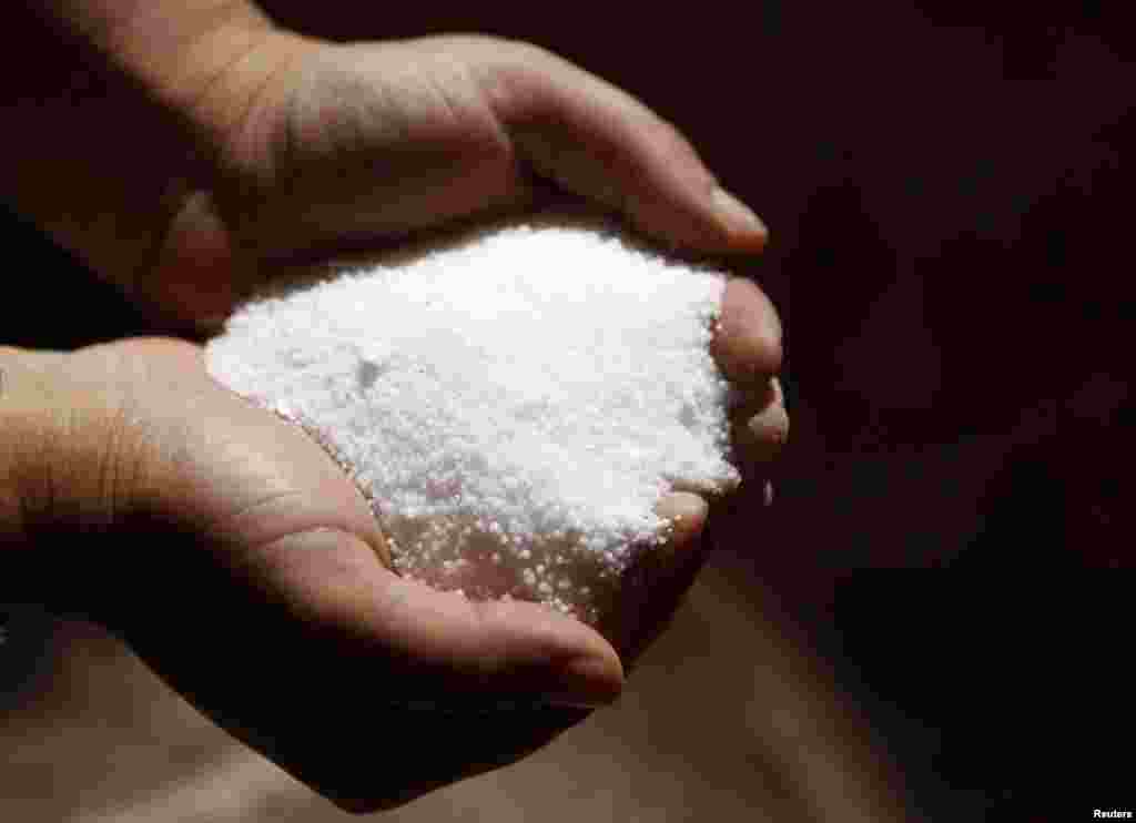 An employee holds processed potassium salts at a Uralkali potash mine.