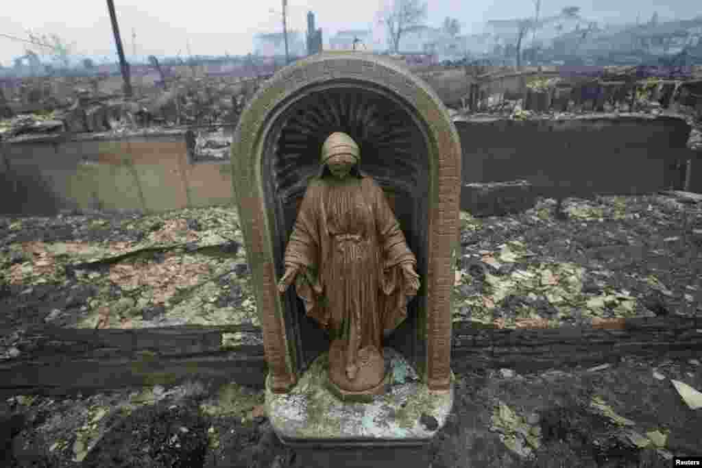 A statue is seen among homes devastated by fire and the effects of Hurricane Sandy in the Breezy Point section of the Queens borough of New York.