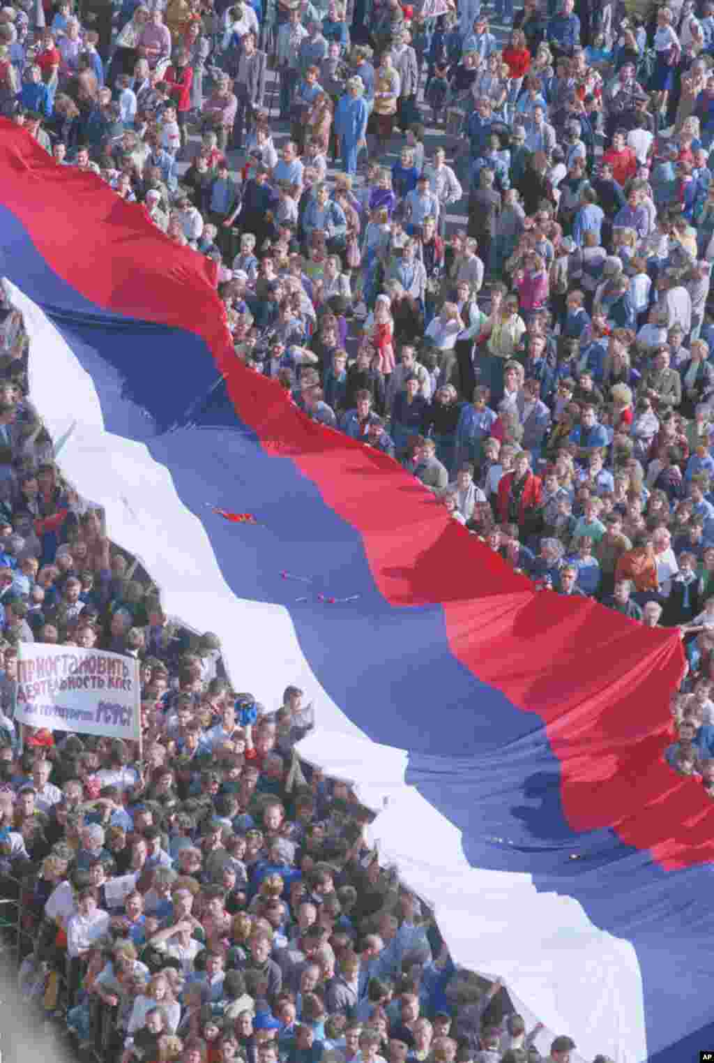 Thousands of jubilant Muscovites march to Red Square in Moscow on August 22, 1991, carrying a giant Russian flag.