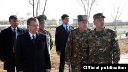 President Shavkat Mirziyoev (left, with army officers) has sought to publicly distance himself from old security practices.