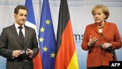 French President Nicolas Sarkozy (left) and German Chancellor Angela Merkel speak to reporters in Munich.