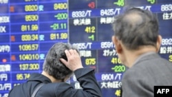 Pedestrians look at a share prices board in Tokyo on April 28 after share prices fell amid fears over the swine-flu outbreak.