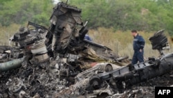 Responders stand amid aircraft parts at the crash site one day after Malaysia Airlines Flight MH17 crashed on July 19, with 298 people from 11 countries aboard, in a field near the town of Shaktarsk, in rebel-held eastern Ukraine.