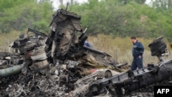 Emergency workers stand at the crash site of a Malaysian airliner, which went to ground on July 17, killing all 298 people on board. 