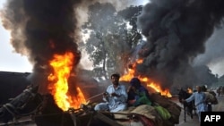 Local residents pass beside burning NATO oil tankers following an attack by the Taliban in Nowshera, Pakistan