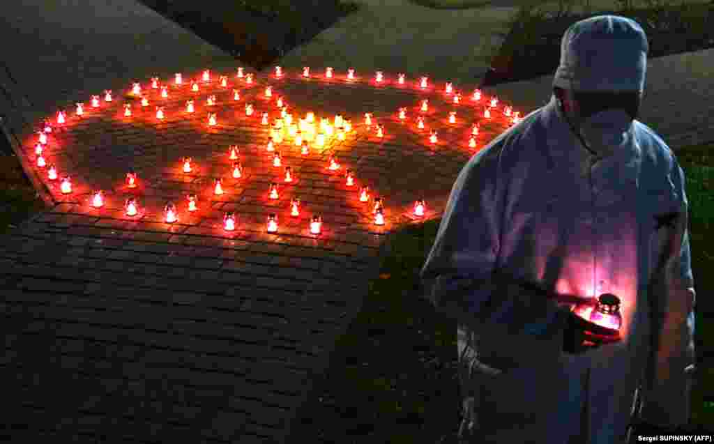 A Chernobyl power plant employee holds a candle near a memorial in the shape of a radioactivity sign in the Ukrainian city of Slavutych on April 25.&nbsp; Many of power station&#39;s personnel lived in&nbsp;Slavutych, located some 50 kilometers from Chernobyl.