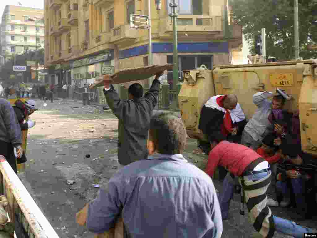 Demonstrators take cover during rioting between pro- and anti-Mubarak demonstrators in Tahrir Square.