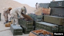 IS fighters search weapons boxes at a Russian base in what is said to be Palmyra, in this still image taken from video uploaded to social media on December 13.