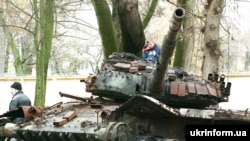 A boy climbs on a destroyed Russian tank in Chernihiv. 