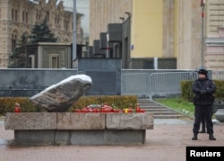 A police officer looks on as candles and flowers are placed at the Solovetsky Stone memorial for the victims of political repression in Moscow on October 29.