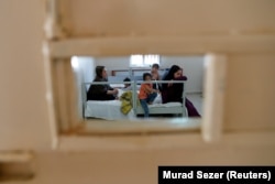 A migrant family from Afghanistan, caught by Turkish security forces after crossing illegally into Turkey from Iran, waits in a room at a migrant processing center in the border city of Van in August 2021.