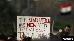 Egyptian protesters hold up a sign outside the Egyptian television center in Cairo in February during antigovernment protests. Al-Jazeera in many ways led the coverage of the protests.