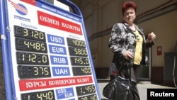 A woman passes by a currency exchange office in the Belarusian capital, Minsk