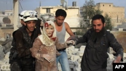 Syrian rescue workers and residents help an injured woman following a reported air strike by government forces on the rebel-held neighborhood of Haydariya in the northern city of Aleppo on April 10.