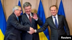 Ukrainian President Petro Poroshenko (center) shakes hands with European Commission President Jean-Claude Juncker (left) and European Council President Donald Tusk at the EU Council in Brussels on March 17.