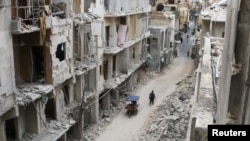 Residents walk near damaged buildings in the rebel-held area of Old Aleppo on May 5.