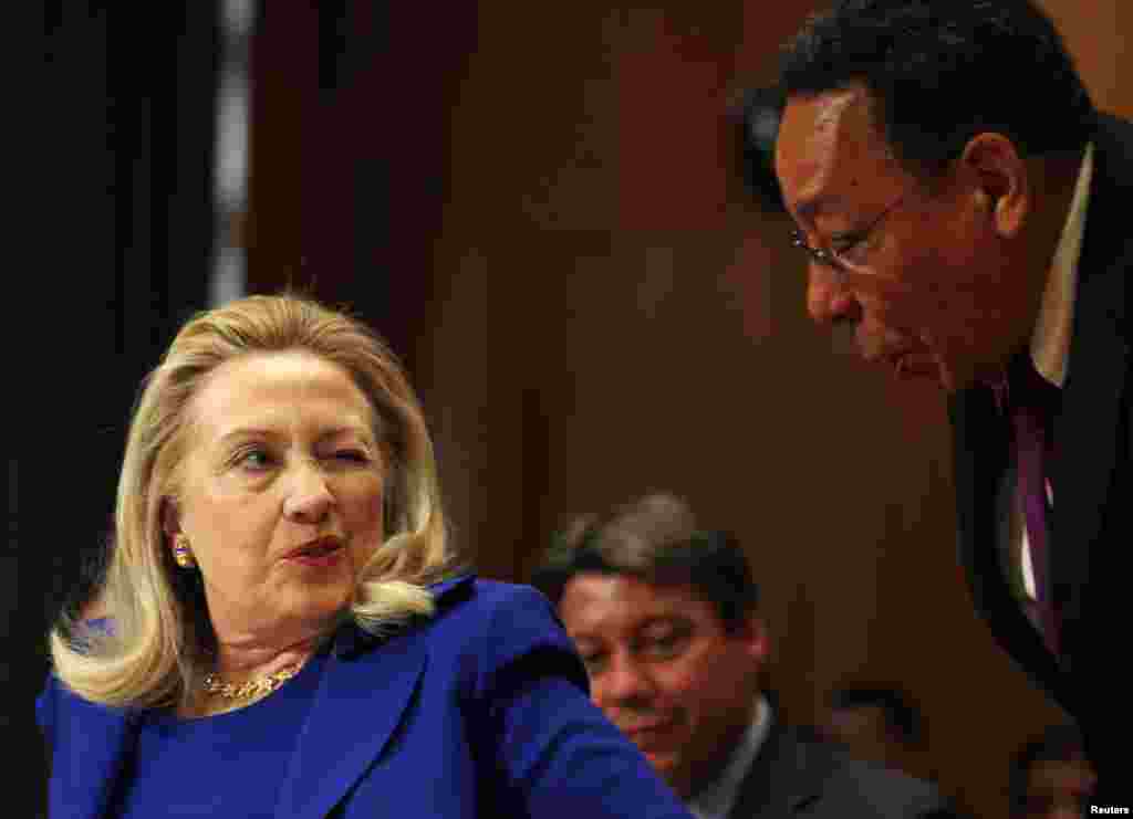 Secretary of State Hillary Clinton (left) winks after being handed a pillow for her back while speaking at the Senate Appropriations Committee about the 2013 budget request in Washington on February 28, 2012.