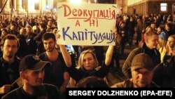 Ukrainians hold a banner reading "Deoccupation but not capitulation!" during a protest against signing on to the Steinmeier Formula in Kyiv on October 2.