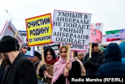 Rally participants hold placards saying "We will rid the motherland of parasites" and "A smart person doesn't become a liberal. A smart person avoids liberals."