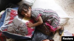 A Syrian girl lies on top of luggage at a makeshift refugee camp inside Iraq after crossing the Iraqi-Syrian border at Abu Kamal-Qaim, the main border post between the two countries, on July 24.