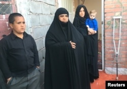 An Afghan refugee family stands outside their shelter at the Bardsir settlement for Afghan refugees in Kerman Province, Iran. Iranians are campaigning for Afghan children to be given the right to go to school in the Islamic republic.