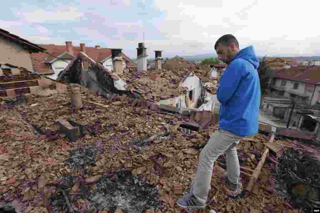 A resident visits destroyed houses in a neighborhood where a gunbattle took place between Macedonian police and an armed group in the town of Kumanovo.