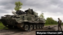 A Ukrainian serviceman walks past a destroyed Russian APC north of Kharkiv (file photo)