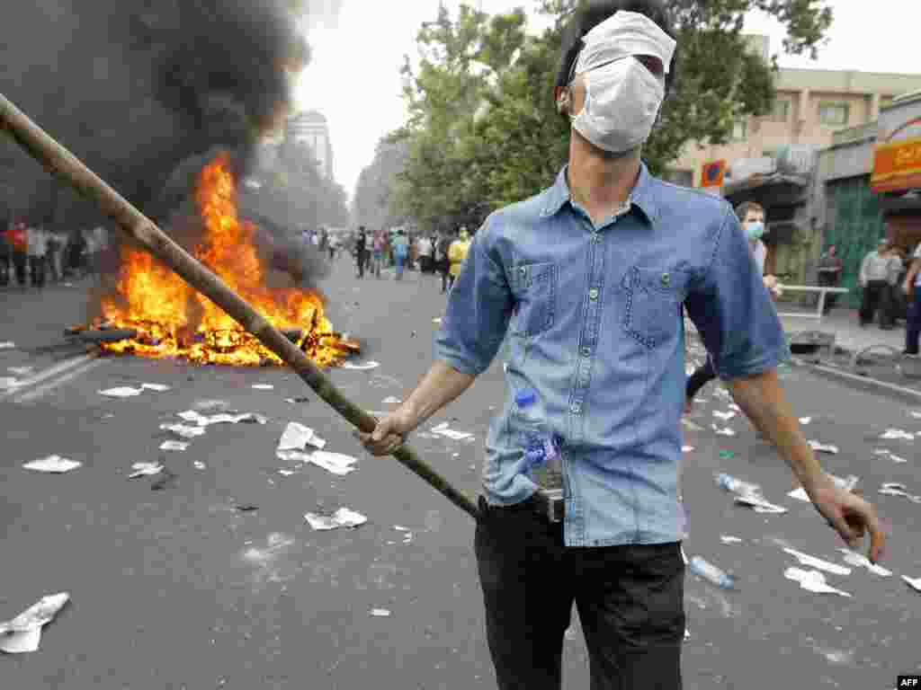 A Musavi supporter walks past a burning motorcycle during the opposition protests.