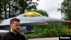 Ukrainian President Volodymyr Zelenskiy speaks in a front of an F-16 fighter jet after marking the Day of the Ukrainian Air Forces at an undisclosed location on August 4.