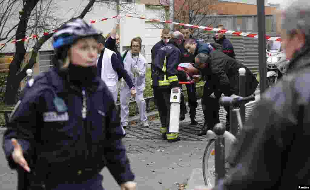 Firefighters carry a victim on a stretcher outside the publication&#39;s offices.