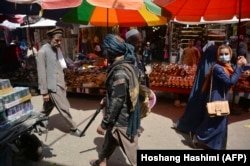 A Taliban fighter walks past shoppers at the Mandawi market in Kabul on September 1.