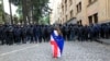 A demonstrator draped in the Georgian national and EU flags stands in front of police blocking the way to the parliament building in Tbilisi during an opposition protest against a controversial "foreign agent" law in May. 