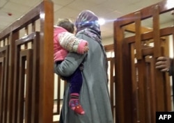 Melina Boughedir carries her son as she arrives at a court in Baghdad on February 19, 2018.