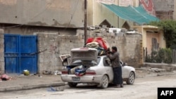 A man fills his car with personal belongings as families leave insecure neighborhoods in the flashpoint city of Fallujah. 