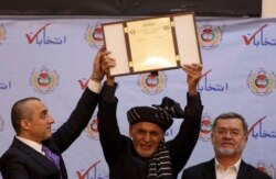 Afghan President Ashraf Ghani (center) receives the official certificate of winning a second term as president during a ceremony in Kabul on February 19.