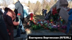 People place flowers on a memorial to repressed Poles and Lithuanians in the village of Pivovarikha in 2019.