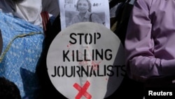 A Pakistani journalist holds a sign and a picture of Associated Press photographer Anja Niedringhaus,, who was killed on April 4, 2014, in Afghanistan, during a demonstration in Islamabad to condemn attacks against journalists.