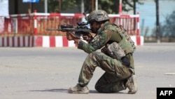 An Afghan National Army commando aims his weapon amid ongoing fighting between Taliban militants and Afghan security forces in Kunduz. 