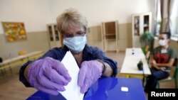 A woman casts her ballot under coronavirus health protocols during the August 30 parliamentary elections. 