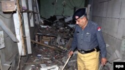 A police official inspects a damaged music shop after a bomb explosion in Charsadda, a town in the Northwest Frontier Province, in 2009.