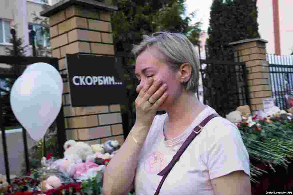 A woman cries near a school in Kazan on May 11. The writing on the wall reads, &quot;We grieve.&quot;