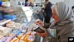 A woman counts her money as she buys a piece of cheese at a city market in Minsk in May.